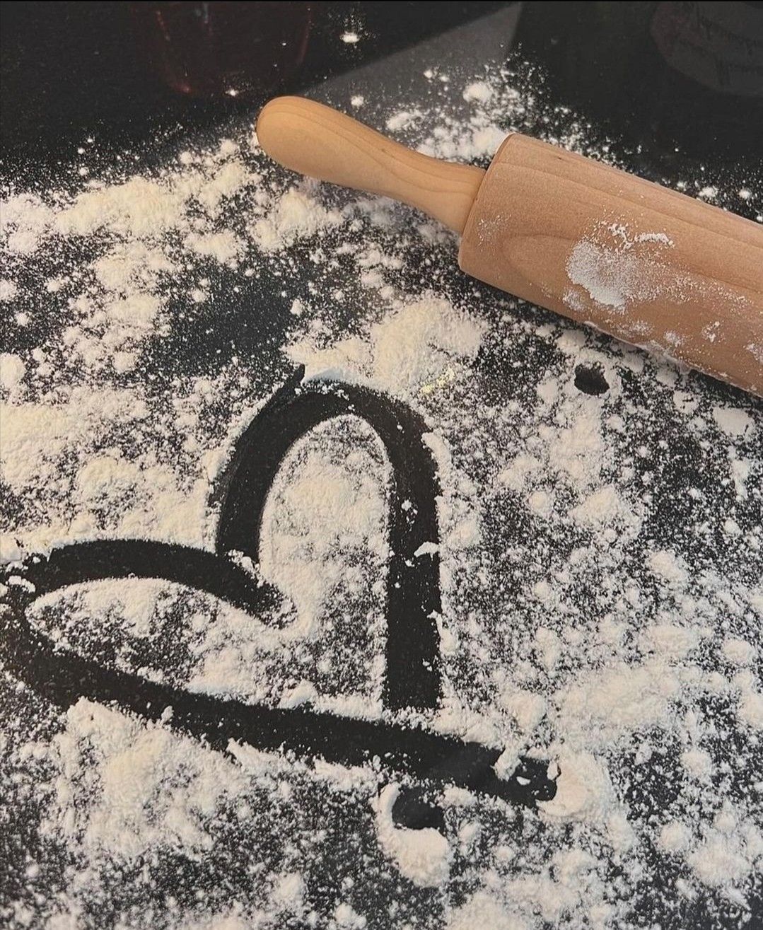 A heart drawn in flour on the counter, next to a rolling pin